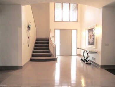 The 2 story foyer with gray wood floors welcomes y