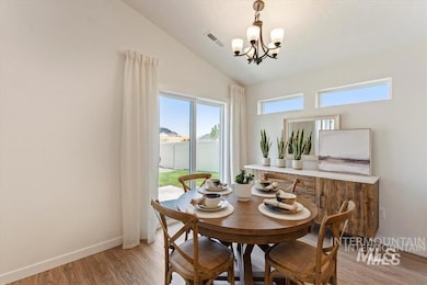 Dining area with light wood finished floors, lofted ceiling, and a chandelier