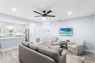 Living room with visible vents, baseboards, light wood-style floors, and a ceiling fan