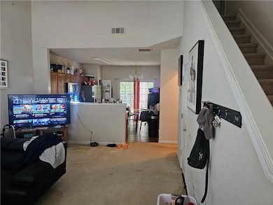 Living room featuring a chandelier, light colored carpet, and stairway