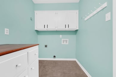 Clothes washing area featuring baseboards, cabinet