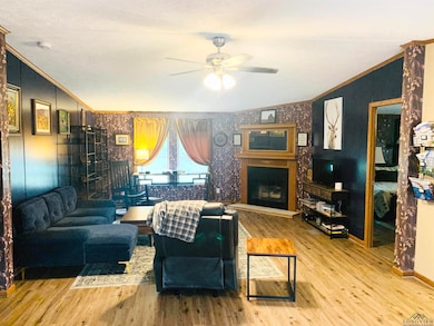 Living room featuring ceiling fan, wallpapered wal