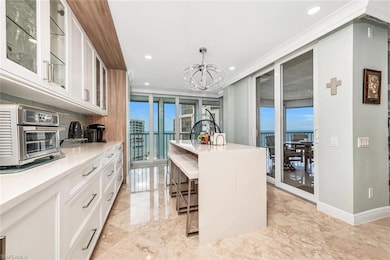 Kitchen featuring a breakfast bar, an inviting chandelier, light countertops, white cabinetry, and recessed lighting