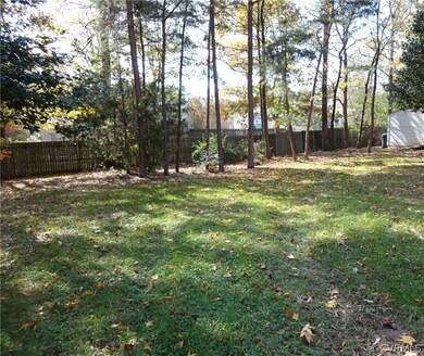 Large level private back yard fringed by trees.