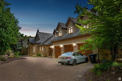 French provincial home with decorative driveway, stone siding, stucco siding, a high end roof, and a garage