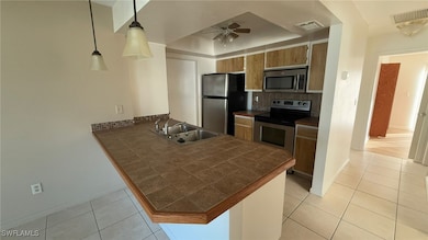 Kitchen with kitchen peninsula, stainless steel appliances, ceiling fan, sink, and hanging light fixtures
