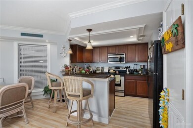 Kitchen with a tray ceiling, hanging light fixtures, stainless steel appliances, and light hardwood / wood-style floors