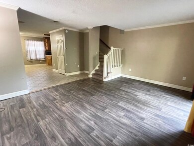 Empty room featuring ornamental molding, wood finished floors, stairway, baseboards, and a textured ceiling