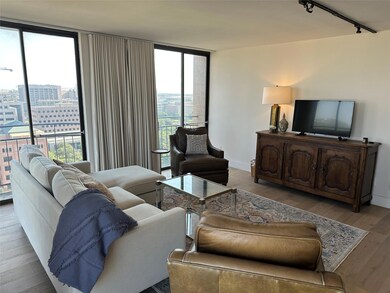 Living area with a wall of windows, wood finished floors, track lighting, and a city view