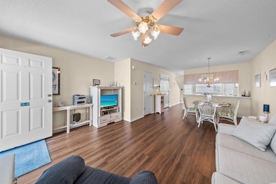 Living room with a chandelier, a textured ceiling, wood finished floors, ceiling fan, and baseboards
