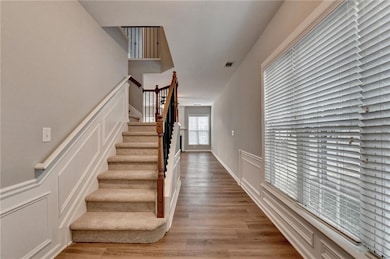 Staircase with a decorative wall, wood finished floors, and a wainscoted wall