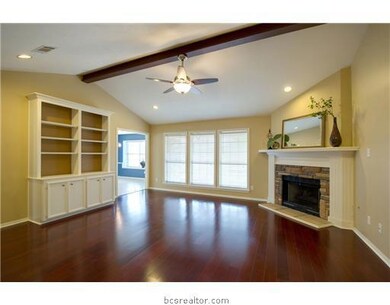 Living Room. The living room features a vaulted ceiling with an exposed beam, a unique stone facade fireplace, built-in media center and large windows that brighten the space with natural light.