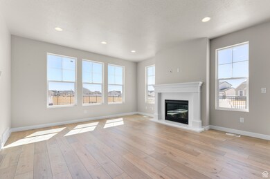 Unfurnished living room with a glass covered fireplace, light wood-type flooring, recessed lighting, and a textured ceiling