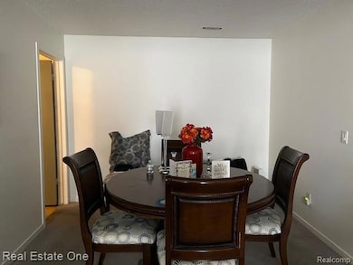 Dining space featuring a textured ceiling and dark carpet