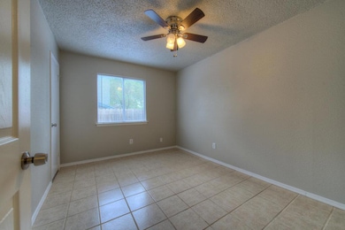 Empty room with a textured ceiling, light tile pa
