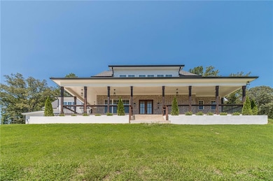 Back of property with covered porch, a yard, and brick siding