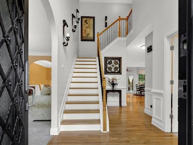 Entryway featuring arched walkways, wood finished floors, a towering ceiling, stairway, and baseboards