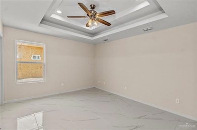 Unfurnished room featuring a raised ceiling and ceiling fan
