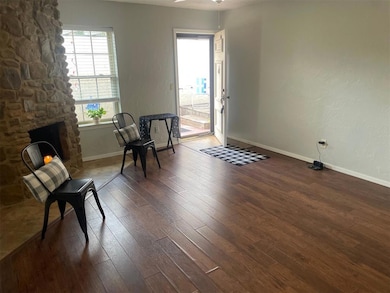 Living area featuring dark wood-style flooring and baseboards