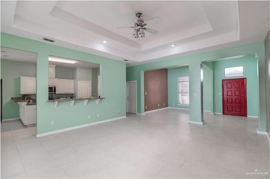 Family, living and view of kitchen with a tray ceiling, a ceiling fan, and recessed lighting