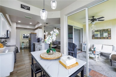 Dining room with ceiling fan, light wood-style flooring, and a tray ceiling