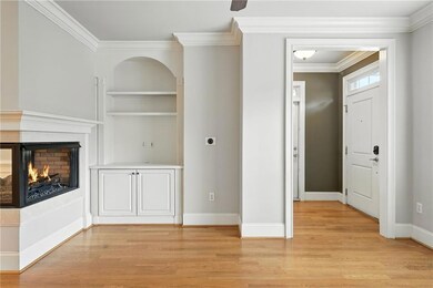 Unfurnished living room with crown molding, a multi sided fireplace, built in features, and light wood-style flooring