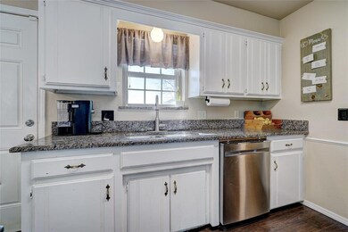 Kitchen featuring white cabinetry, dark hardwood /