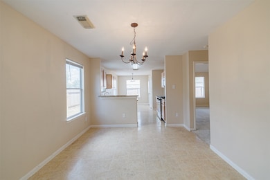 Dining area off kitchen with chandelier lighting and backyard views.