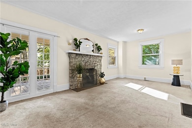 Unfurnished living room with carpet flooring, and a stone fireplace,