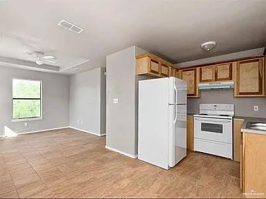 Kitchen featuring white appliances, under cabinet range hood, brown cabinetry, open floor plan, and light countertops