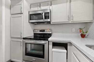 Kitchen with appliances with stainless steel finishes, backsplash, and white cabinets