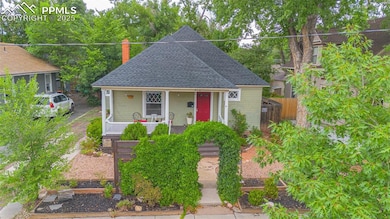 Bungalow-style home with a porch, roof with shingles, fence, and a chimney