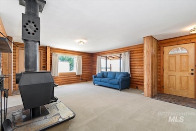 Carpeted living room featuring a wood stove and log walls