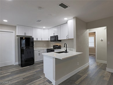 Kitchen featuring black appliances, white cabinetry, a peninsula, dark wood-style floors, and recessed lighting