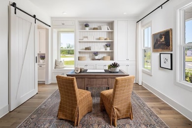 Office featuring a barn door, healthy amount of natural light, wood finished floors, and recessed lighting