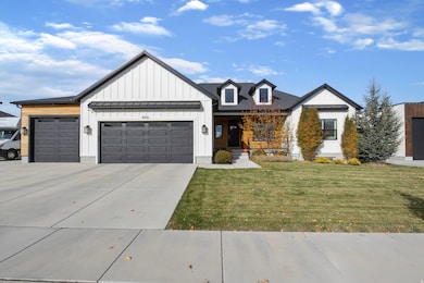 Modern farmhouse with board and batten siding, covered porch, an attached garage, concrete driveway, and a front lawn