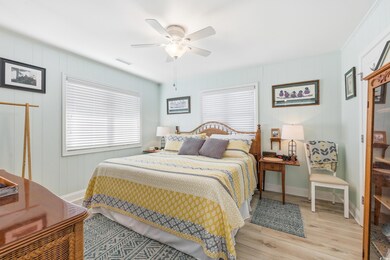Bedroom featuring light wood-type flooring, multiple windows, ceiling fan, and wooden walls