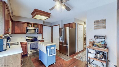 Kitchen featuring stainless steel appliances, light countertops, LVP flooring, ceiling fan, pantry and sliding door to backyard deck.