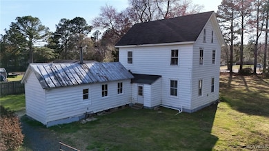 Rear view of property with entry steps, fence, and a lawn
