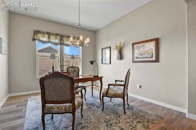 Dining area with wood finished floors, a chandelier, and a desk
