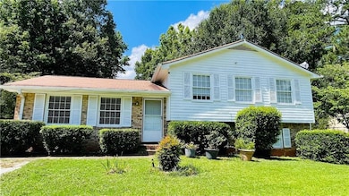 Tri-level home featuring a front lawn and brick siding