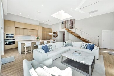 Living area featuring a skylight, stairway, a high ceiling, and light wood-style flooring