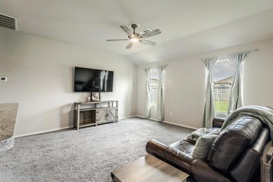 Living room featuring ceiling fan, carpet floors, baseboards, and vaulted ceiling