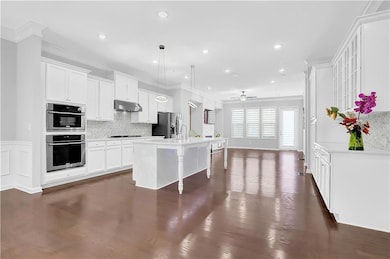 Kitchen with under cabinet range hood, stainless steel appliances, ornamental molding, tasteful backsplash, and a ceiling fan