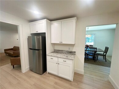 Kitchen with freestanding refrigerator, light wood-style floors, white cabinets, and light stone countertops