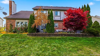 Rear view of property with brick siding, a patio, a lawn, and a chimney