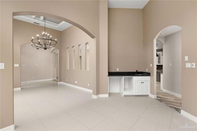 Tiled empty room with a towering ceiling and an inviting chandelier