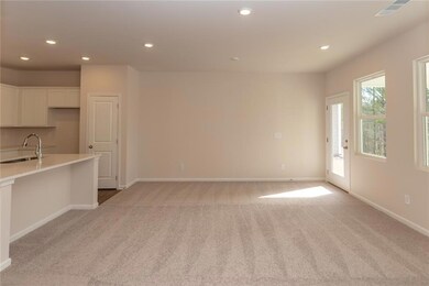 Unfurnished living room featuring a sink, light colored carpet, recessed lighting, and baseboards