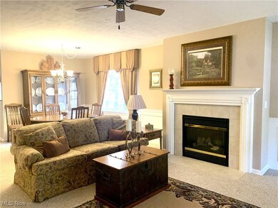 Carpeted great room featuring a gas fireplace and ceiling fan
