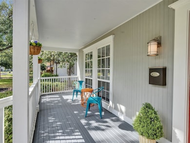 Covered front porch with space for seating and large windows offering a welcoming entrance.